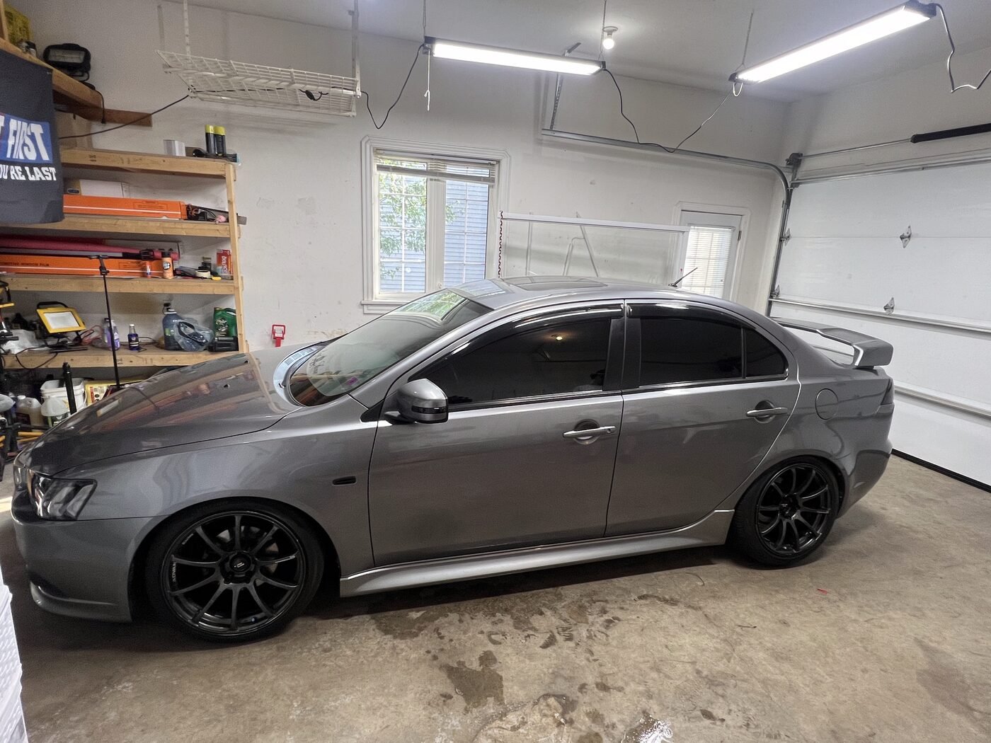 Grey Mitsubishi Lancer inside the Panjab Car Studio shop in Moncton with its windshield and tinted side windows in view